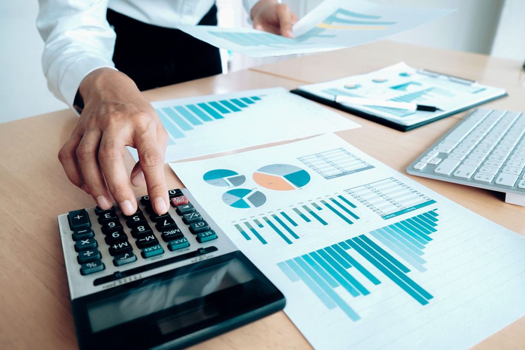 Financial reports and charts being reviewed with a calculator